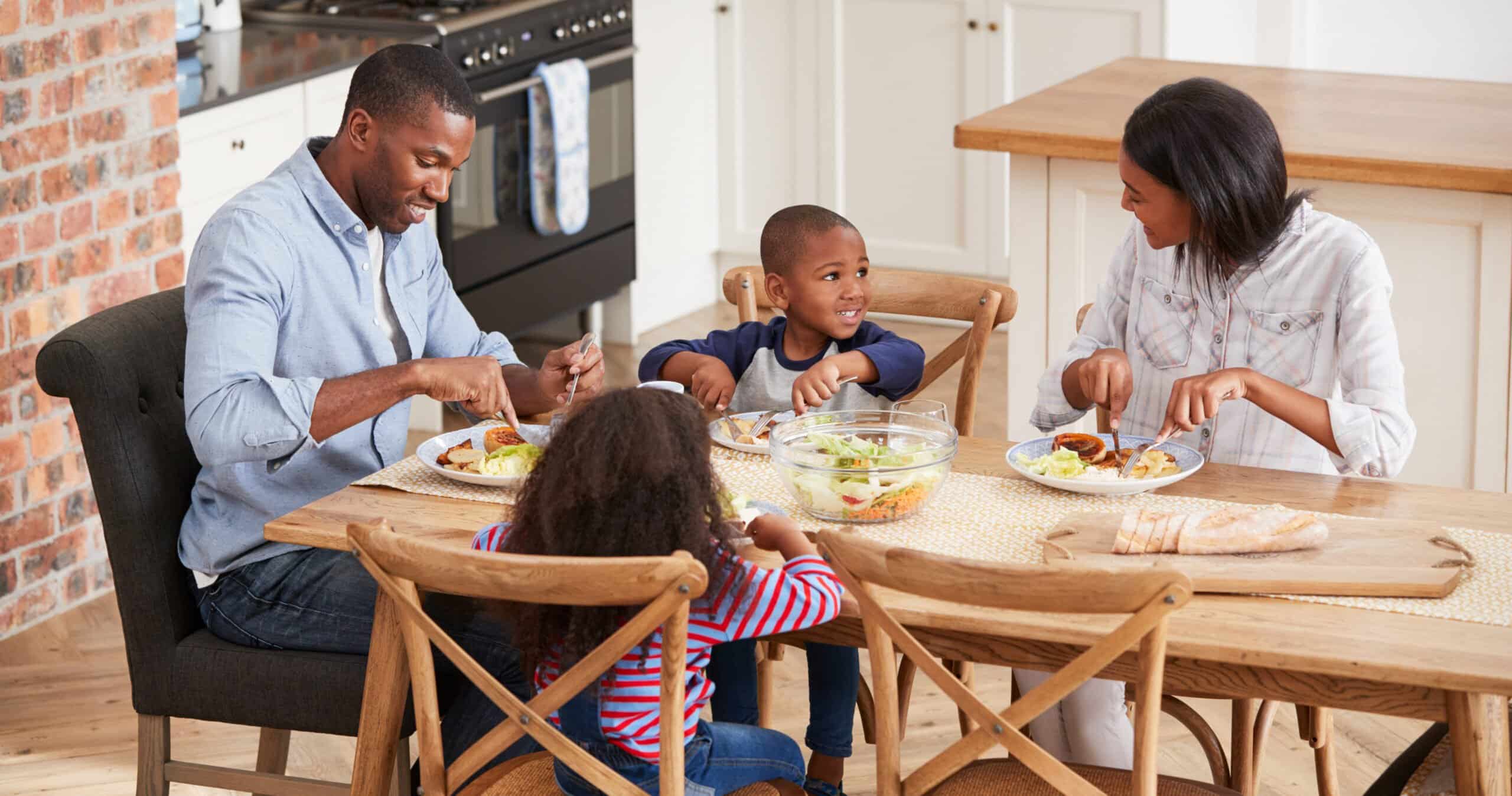 Family enjoying a meal together at a wooden dining table, fostering positive eating habits.
